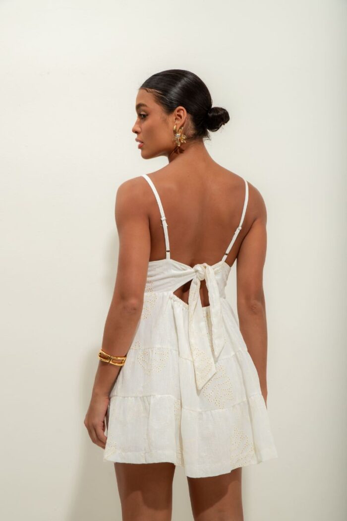 Vestido Elis é curto, forrado e feito em laise de algodão, com alças reguláveis, elástico e amarração nas costas, oferecendo conforto e um ajuste perfeito