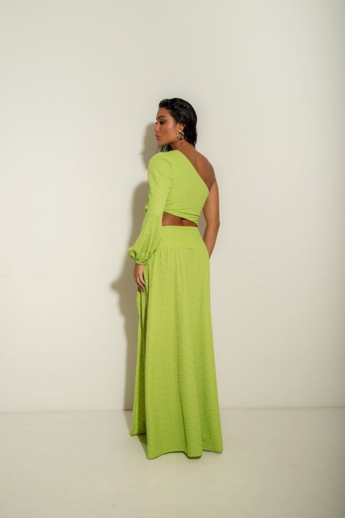 O Vestido Atenas é um modelo de um ombro só, com manga longa, fenda na barriga com detalhe em argola e fenda na perna, oferecendo um visual moderno.