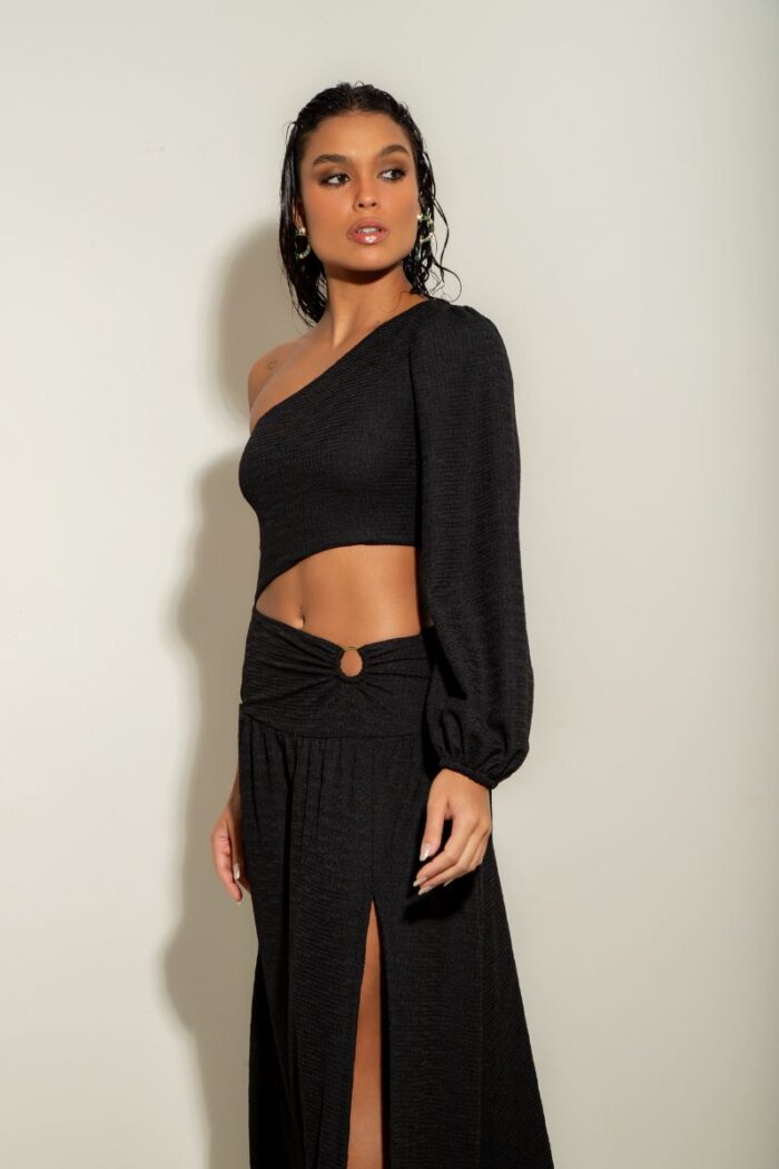 O Vestido Atenas é um modelo de um ombro só, com manga longa, fenda na barriga com detalhe em argola e fenda na perna, oferecendo um visual moderno.