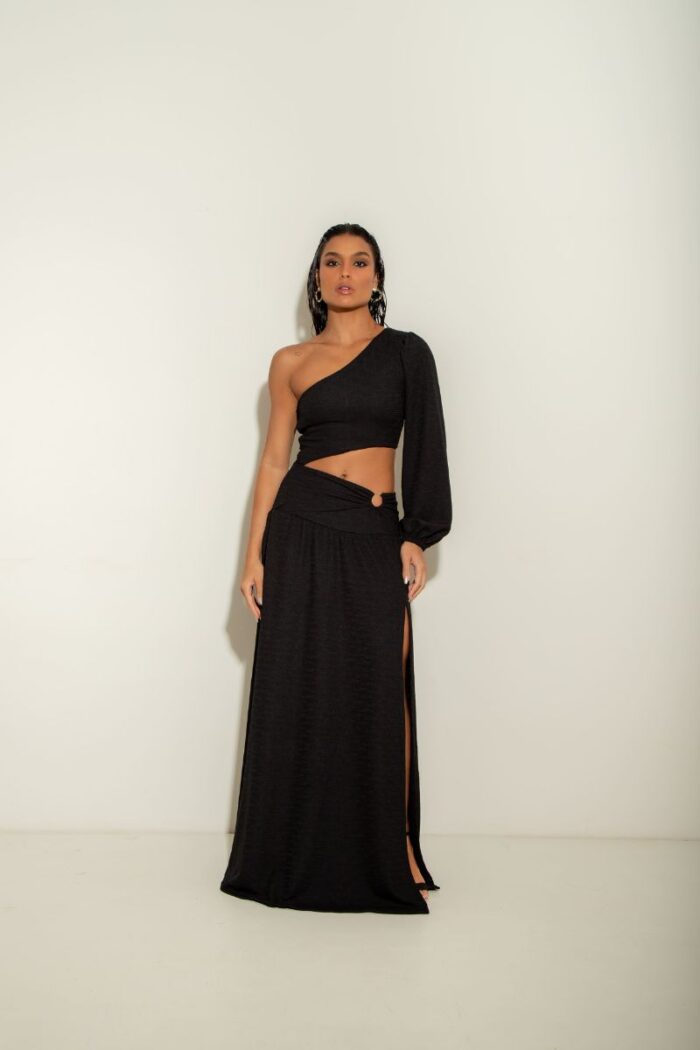 O Vestido Atenas é um modelo de um ombro só, com manga longa, fenda na barriga com detalhe em argola e fenda na perna, oferecendo um visual moderno.