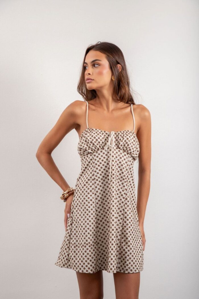 Vestido Elis é curto, forrado e feito em laise de algodão, com alças reguláveis, elástico e amarração nas costas, oferecendo conforto e um ajuste perfeito.